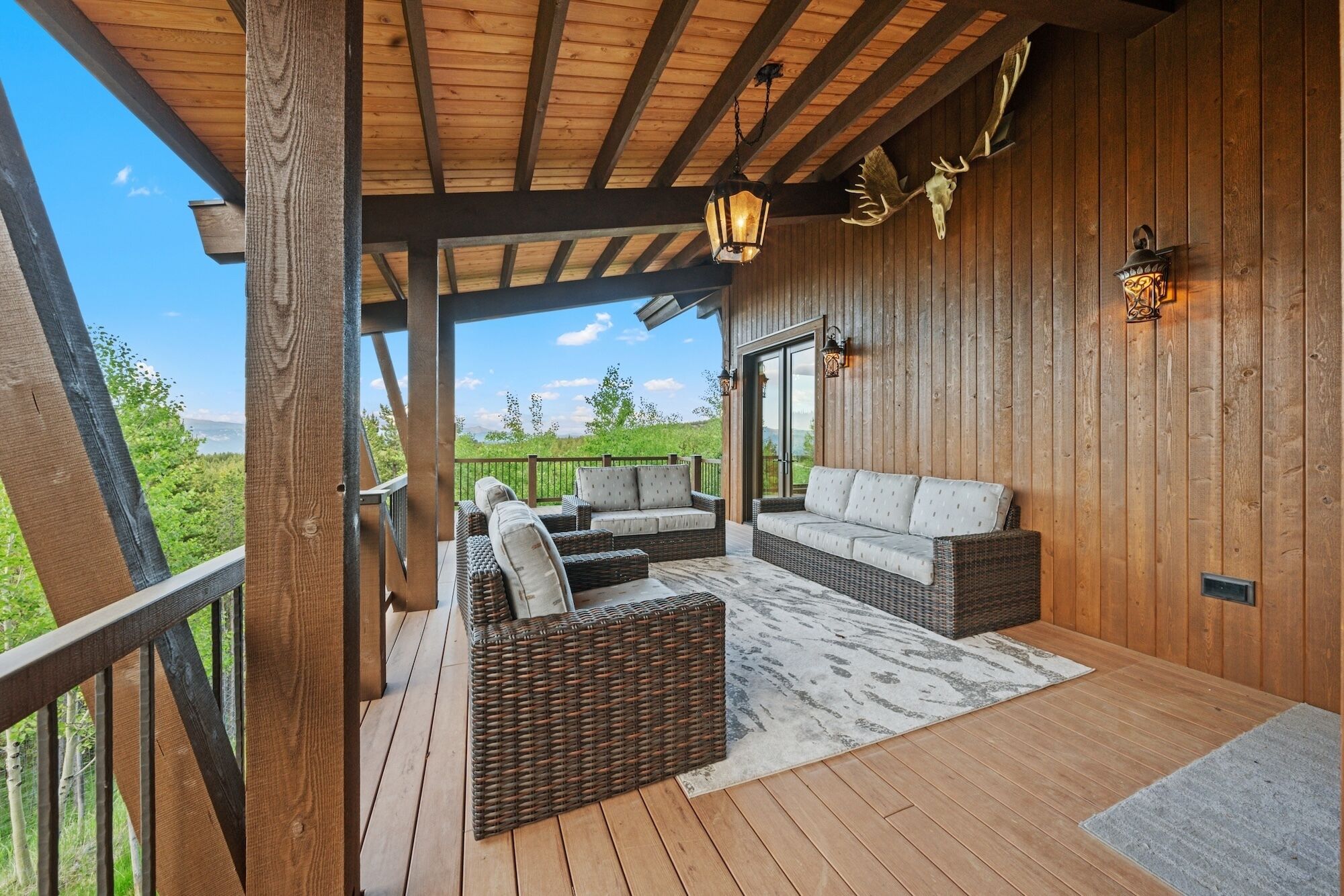 Un espacio al aire libre cubierto con mobiliario de mimbre, una terraza de madera y vistas al paisaje.