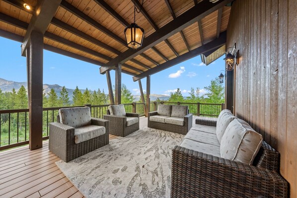 A covered outdoor seating area with wicker furniture and a view of mountains.