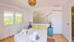 A bedroom with a large bed, a view of the outdoors through a window, a hammock, and a small table with a lamp. - Los Nisperos de Paco (Canillas de Albaida)