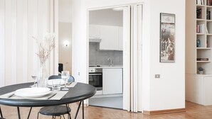 Een modern appartement met een eethoek, keuken en een boekenplank.