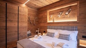 Ein schlicht eingerichtetes Schlafzimmer im Chalet-Stil mit einem Bett, Kissen und einem Wandregal mit Dekoration.