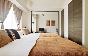 A modern hotel room with a large bed, a TV, and a wardrobe.