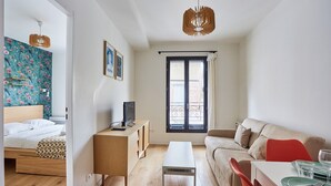 A modern room with a bed, a desk, a sofa, and a dining area.