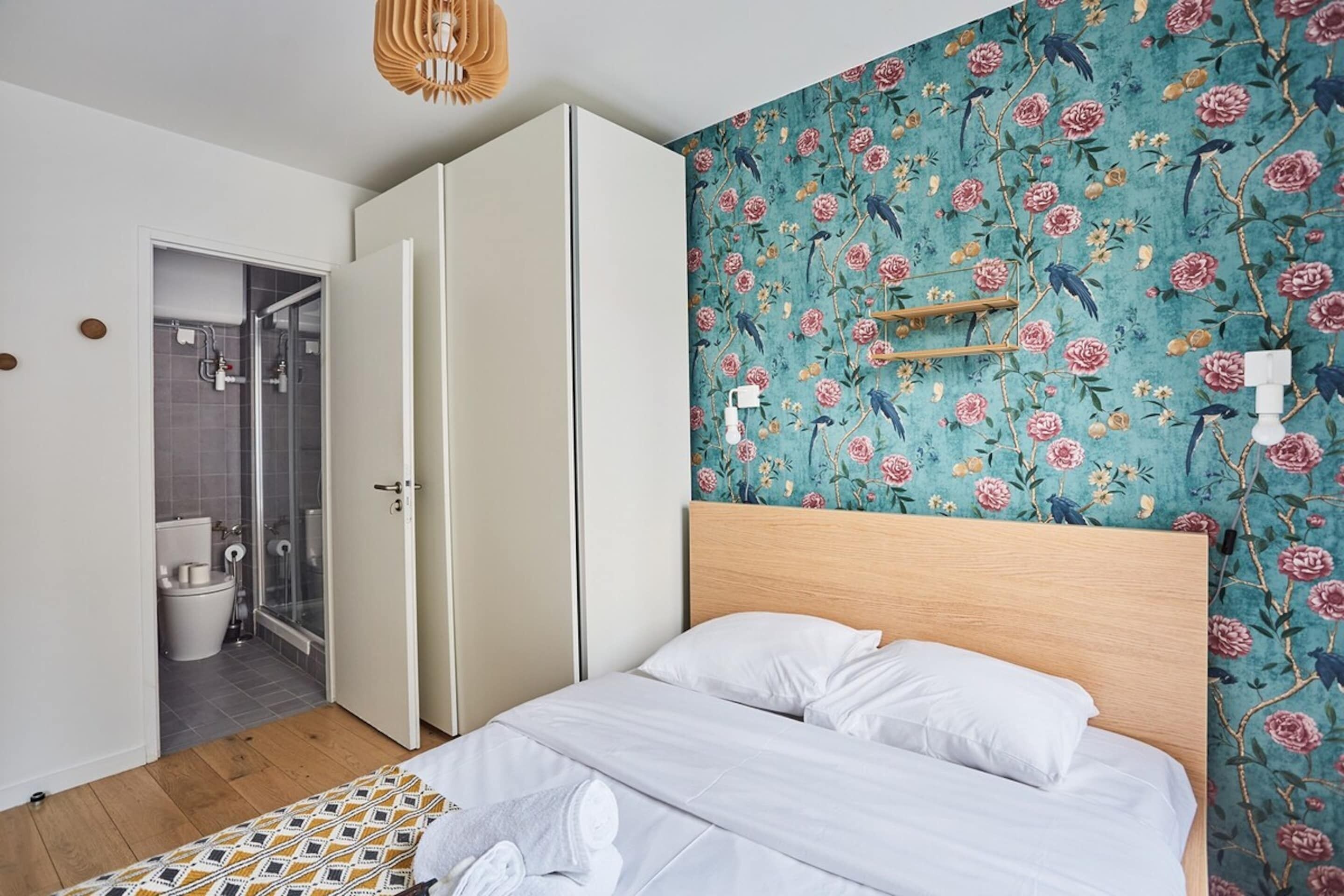 Een slaapkamer met een bed, een houten hoofdbord, een douchegedeelte en een badkamer met toilet en douche.