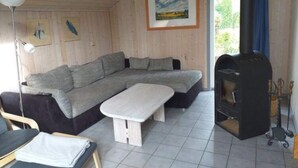 Una sala de estar acogedora con un sofá modular, una mesita blanca y una estufa de leña.