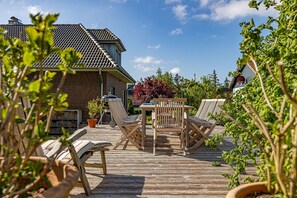 A wooden deck with outdoor furniture, a brick house in the background, and a clear sky. - "Experience Unforgettable Relaxation at Our Beachside Retreat!" (Glücksburg)