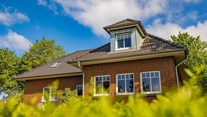 Una casa de ladrillo de dos pisos con techo inclinado, ventanas dormer y un ático visible.