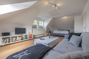 Relax in this stylish living room with a flat-screen TV, bookshelf, and comfortable sofa.