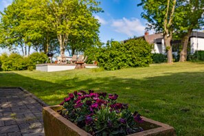 Enjoy outdoor dining and relaxation in this serene garden setting, featuring a barbecue grill and lush greenery.