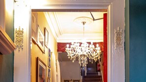 A hallway with a chandelier, a staircase, and a red carpet. - Hotel Rouge (Blackpool)