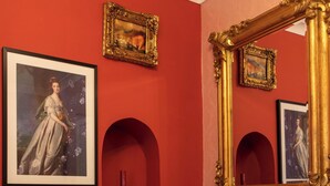 A room with red walls, a large ornate mirror, and two framed pictures. - Hotel Rouge (Blackpool)
