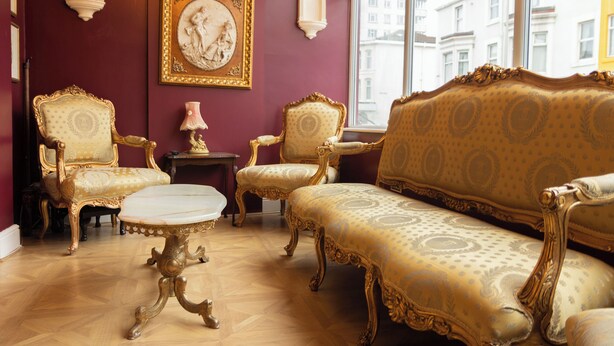 A room with a patterned sofa, two ornate chairs, a small table, and a framed artwork on the wall. - Hotel Rouge (Blackpool)