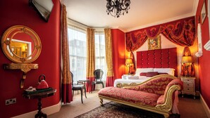 A luxurious bedroom with a large bed, a sitting area, and a view of the city. - Hotel Rouge (Blackpool)