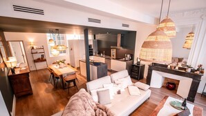Una sala de estar moderna con sofá, comedor, cocina y chimenea.