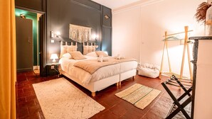 Un dormitorio con una cama grande, lámparas de noche, una lámpara colgante y suelo de madera.