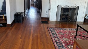 Un salon spacieux doté d’un parquet, d’une cheminée, d’un téléviseur et d’un tapis à motifs.