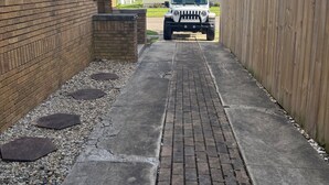 Un étroit sentier pavé mène à un véhicule blanc garé dans une allée.