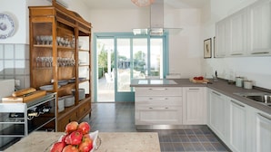 A modern kitchen with white cabinets, a large wooden wine rack, and a view to the outside. - Villa in Trapani With Private Pool & Near Sea (Paceco)