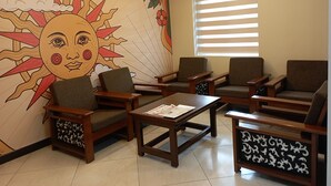 A room with a mural of a sun and clouds, wooden furniture, and a window with blinds. - Hotel Sunbright Residency - Manipal (Udupi)