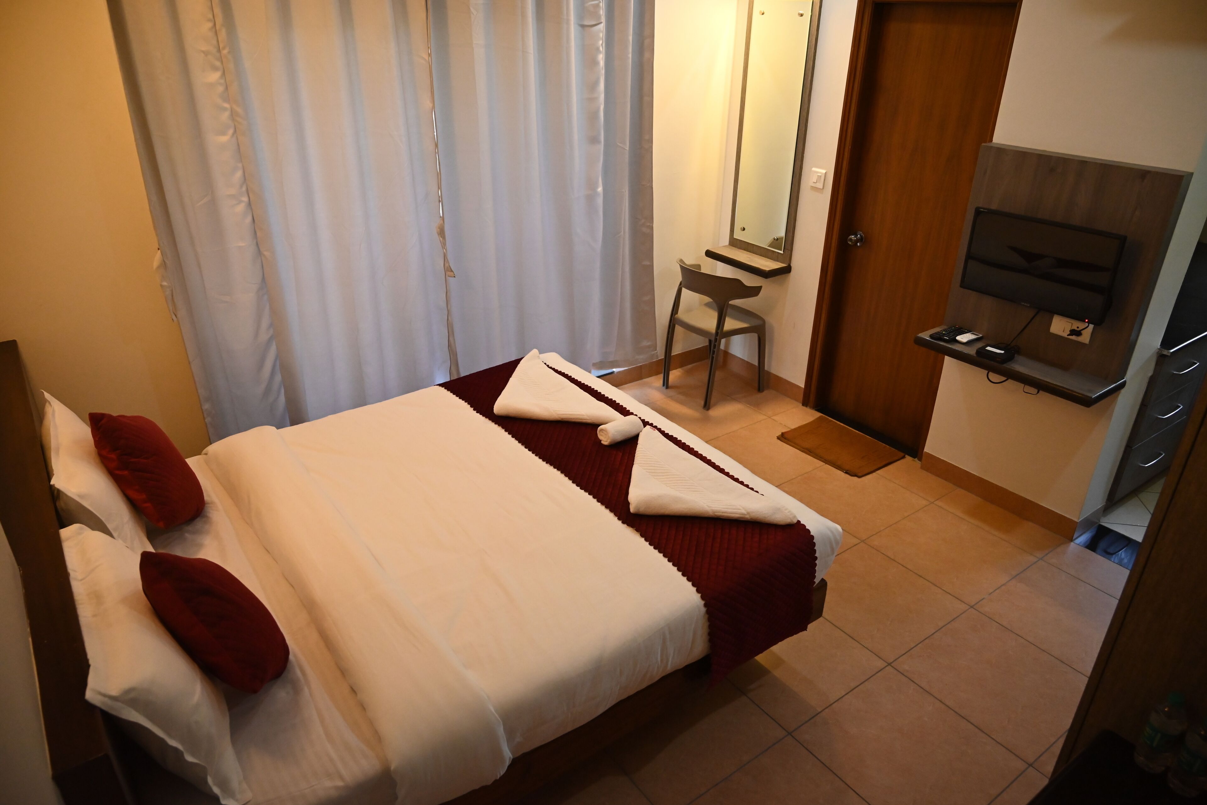 A hotel room with a bed, a chair, a TV, and a desk.