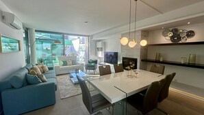 A modern living room with a sofa, a dining table, and a TV.