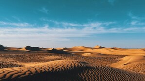 Un paysage désertique avec des dunes de sable sous un ciel dégagé.