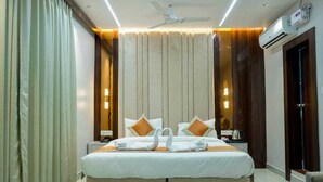 Ein Hotelzimmer mit einem großen Bett, einem Deckenventilator, einer Klimaanlage und Vorhängen.