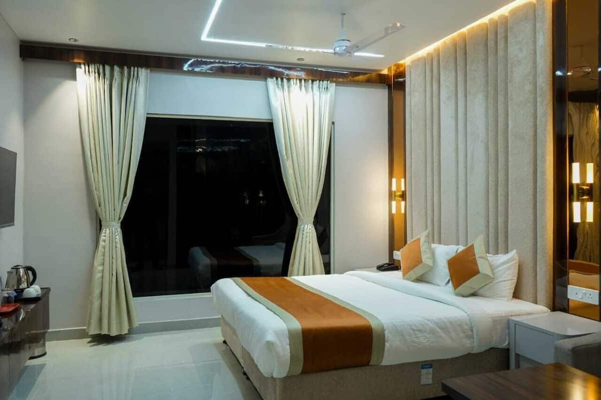 A modern hotel room with a large bed, curtains, a bedside table, a nightstand, and a window.