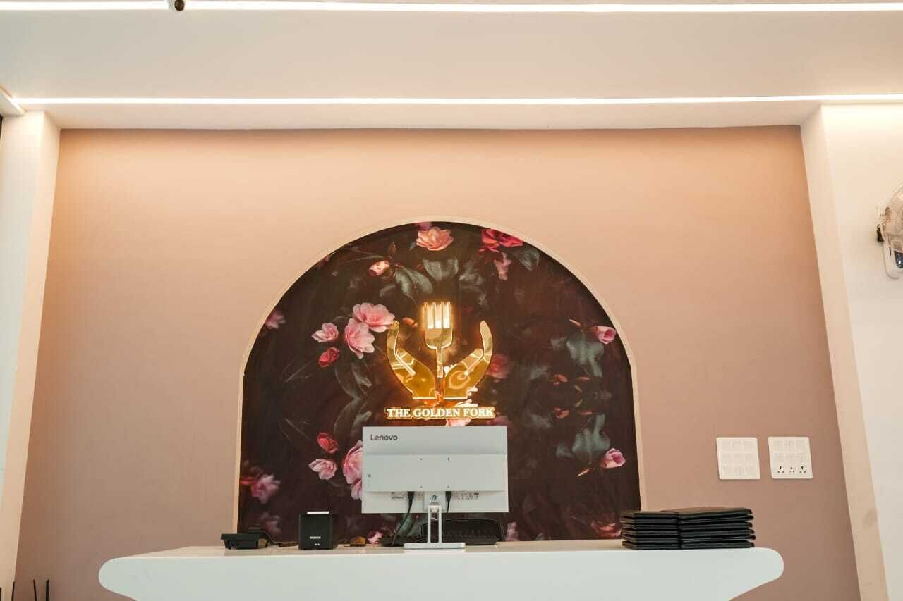 A reception desk with a floral backdrop and a sign reading "The Golden Fork."