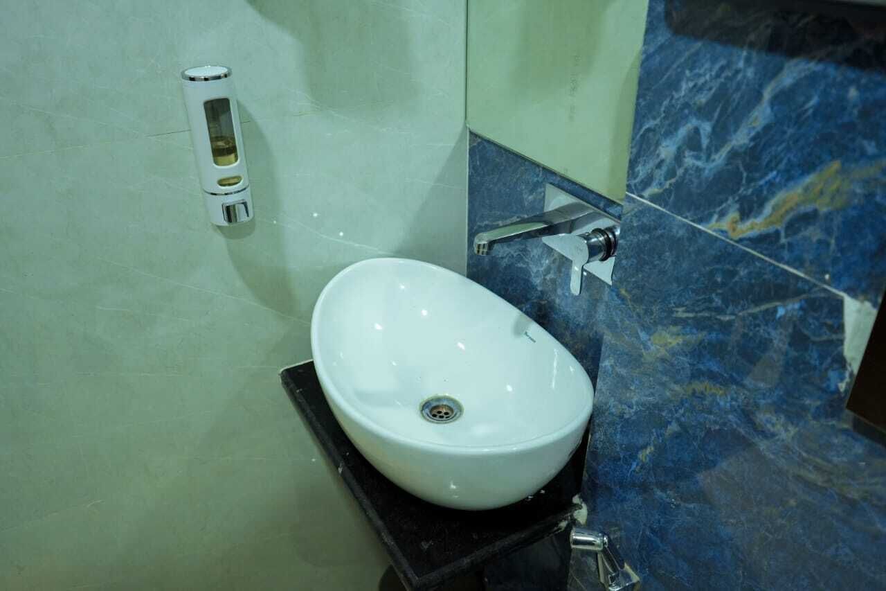 Un baño con un lavabo blanco, un espejo y una pared revestida de mármol.