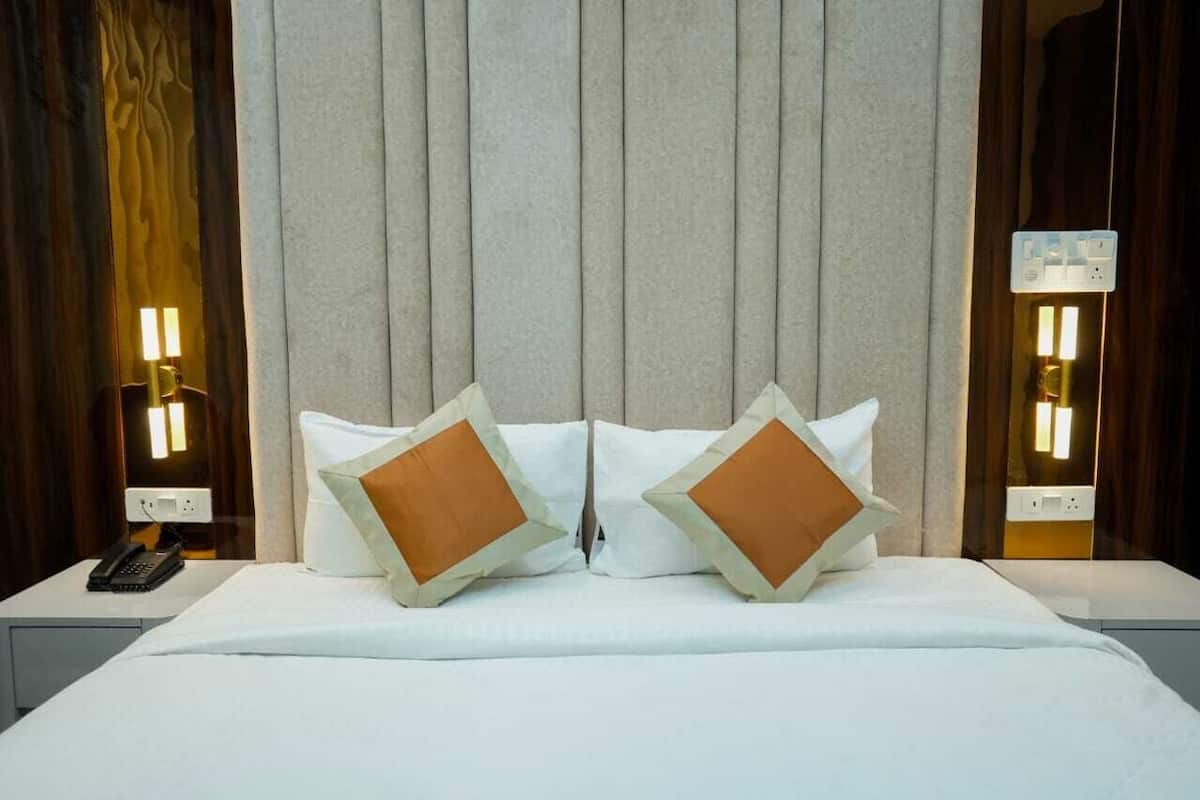 A hotel room with a large bed, two bedside lamps, and a telephone on the nightstand.