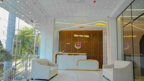 Ein moderner Empfangsbereich mit Glaswand, zwei weißen Sofas und einer Rezeption.