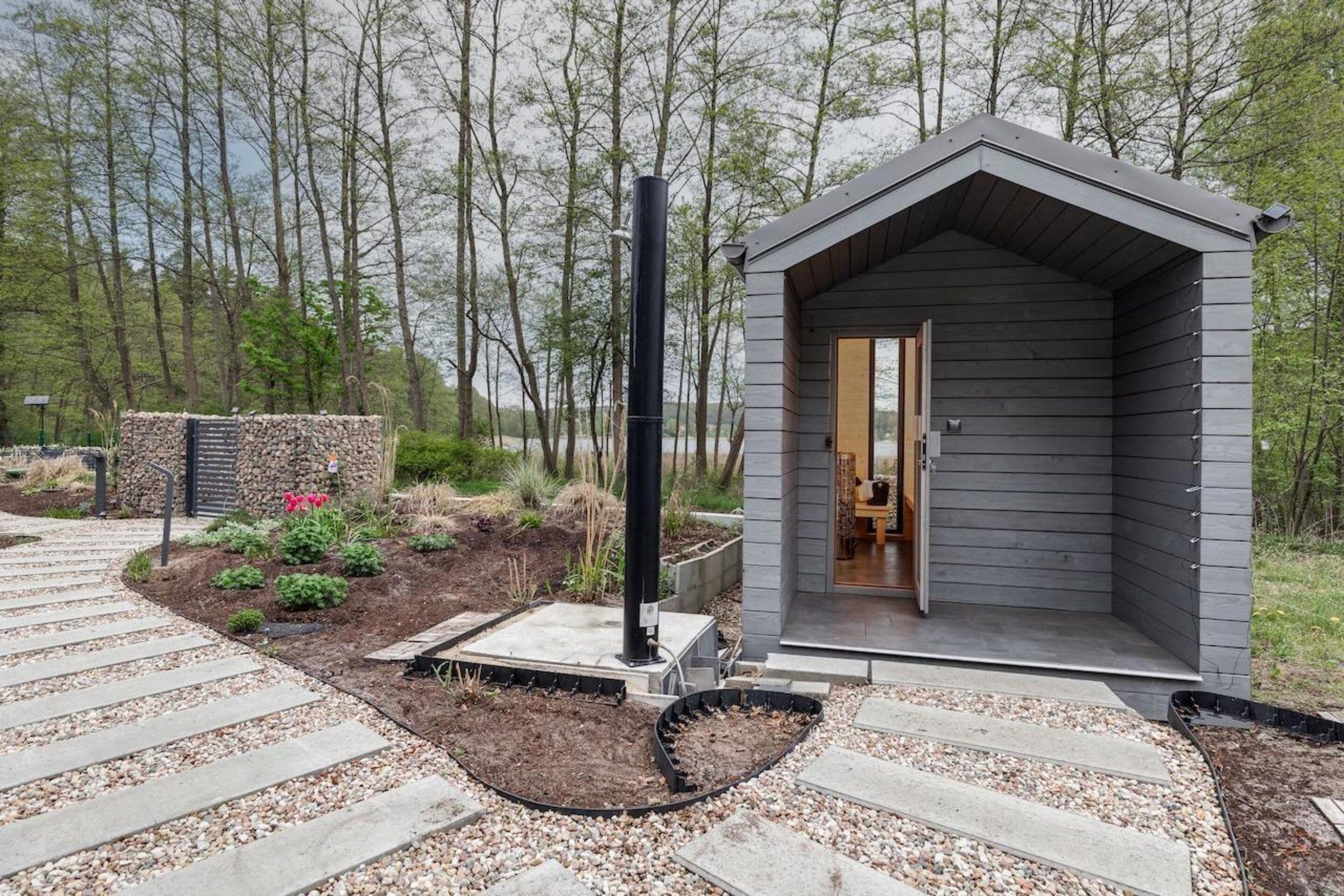 Una cabaña pequeña de un solo piso con techo inclinado, una chimenea y una puerta de acceso.