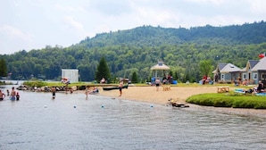 Un resort junto al lago con un pabellón, playa y cabañas.