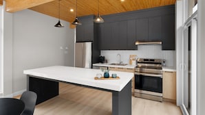 Una cocina moderna con una isla central, electrodomésticos de acero inoxidable y techo de madera.