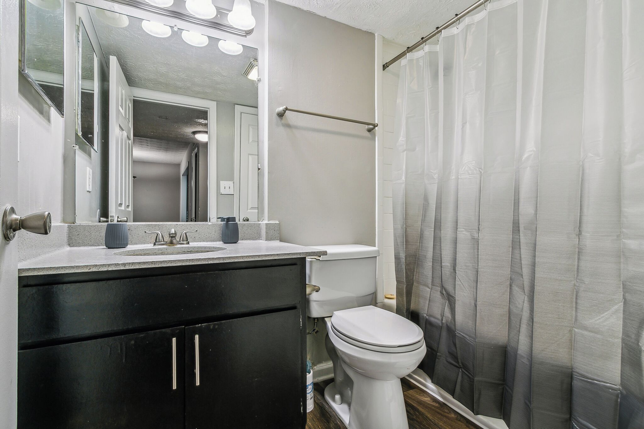 A bathroom with a toilet, sink, mirror, and shower curtain.