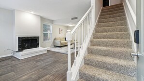 Ein Wohnzimmer mit Kamin, Treppe und einer Couch.