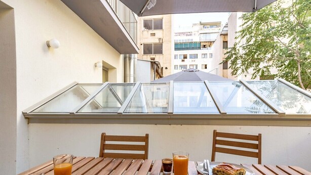 A balcony with a table set for breakfast, including croissants, juice, and a plate of food.