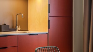 A compact kitchen with a single sink, a small table, and a chair.