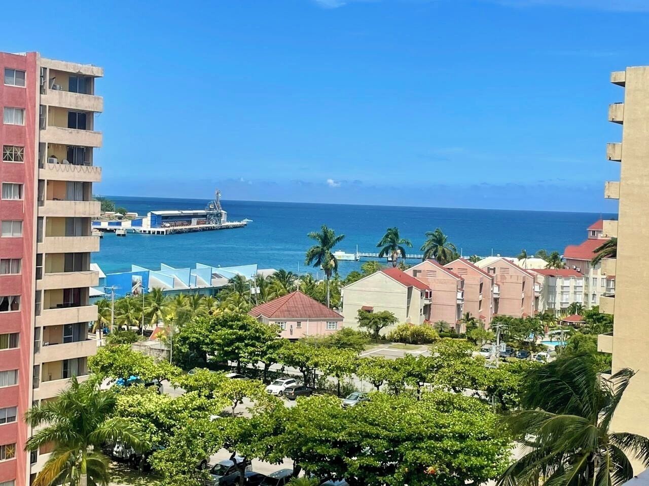 Un hôtel situé sur la côte, avec plusieurs étages, une vue sur la mer et un bateau amarré à proximité.