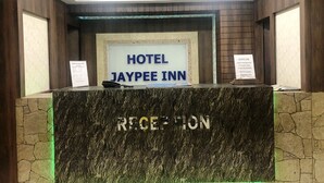 Ένας πάγκος υποδοχής στο ξενοδοχείο Jaypee Inn, με μαρμάρινη επιφάνεια και έναν ανεμιστήρα οροφής ακριβώς από πάνω.