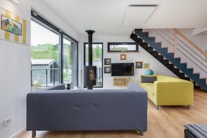 A modern living room with a sofa, a television, and a fireplace. - Holiday Home by Lake Wiselka, Near Baltic Beach (gmina Wolin)