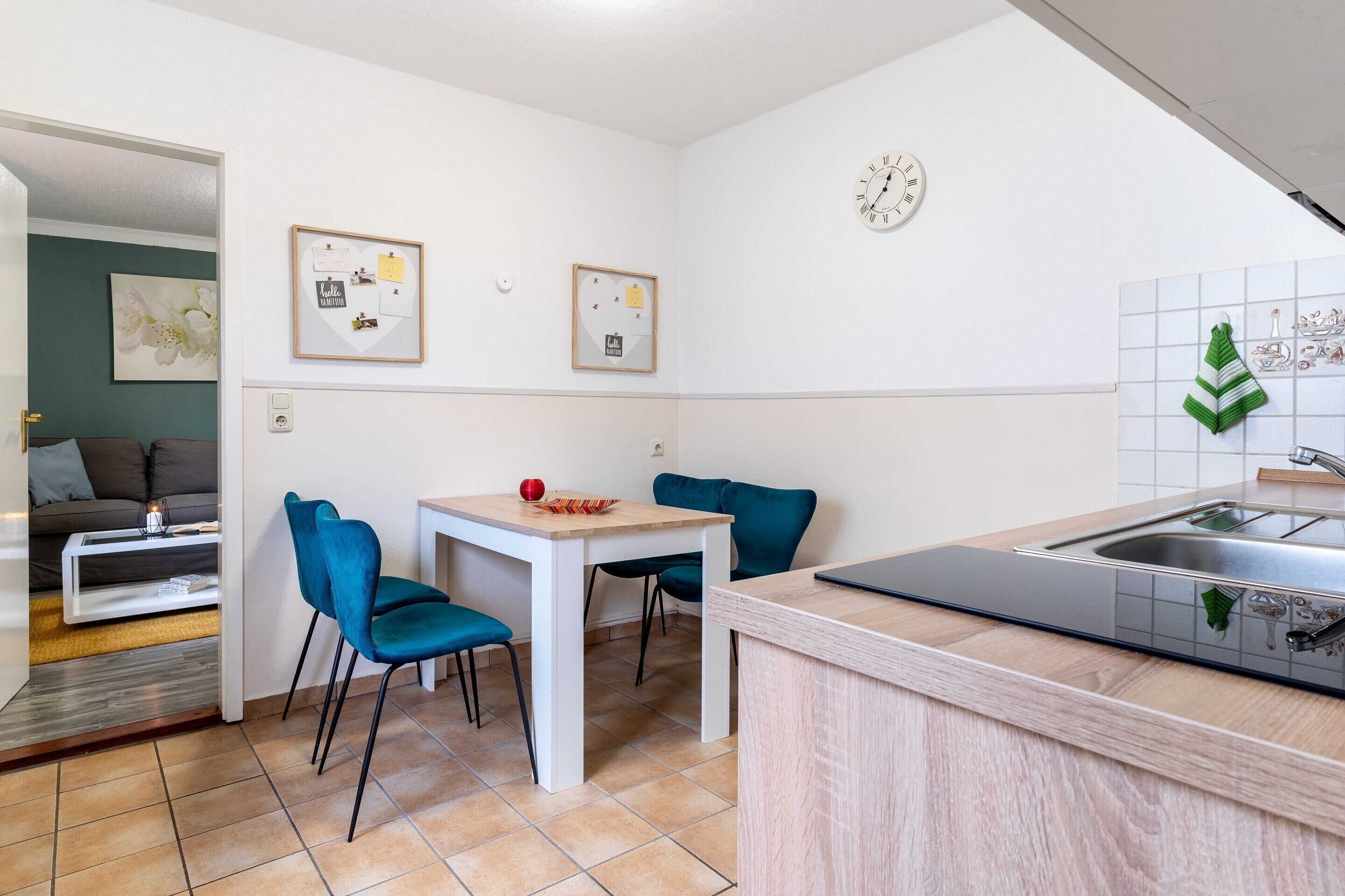 Une cuisine compacte comprenant un coin repas, un évier et une horloge murale.