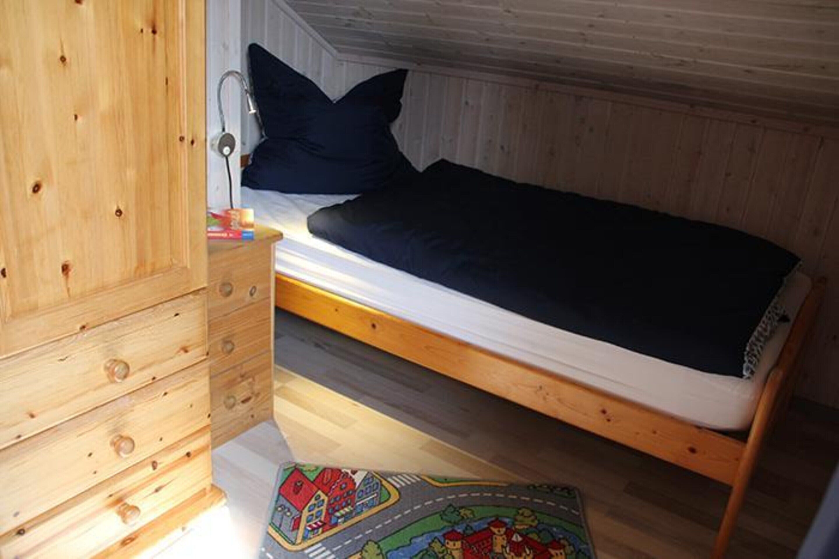 Une petite chambre avec un lit simple, une armoire en bois et une table de chevet.