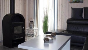 A modern living room with a black wood-burning stove, a white coffee table, and a black leather sofa. - Ferienpark Mirow in Granzow (Mirow)