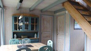 A dining area with a wooden table, teal chairs, and a cabinet with glass doors. - Ferienpark Mirow in Granzow (Mirow)