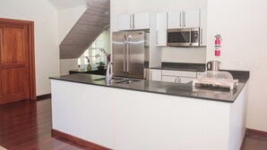 Une cuisine moderne dotée d’appareils électroménagers en acier inoxydable, de meubles blancs et d’un escalier en bois.
