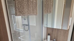 A modern bathroom with a glass shower enclosure, a white sink, and a wooden vanity. - Shadow Escapes, Shadow Escapes - Morning Rising (Ladybank)