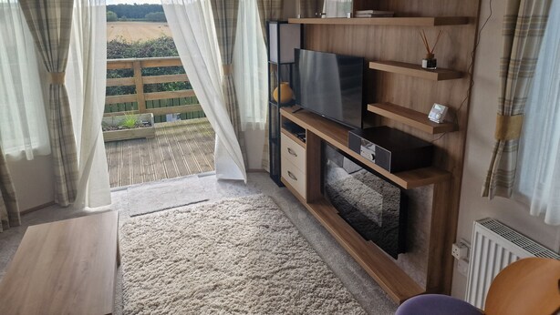 A modern living room with a large TV, wooden shelves, and a view of a garden through sheer curtains. - Shadow Escapes, Shadow Escapes - Morning Rising (Ladybank)