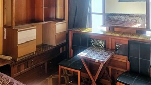 A room with a wooden cabinet, a table with chairs, a chandelier, and a window with curtains. - Room-private Room Antwerpen (Antwerp)